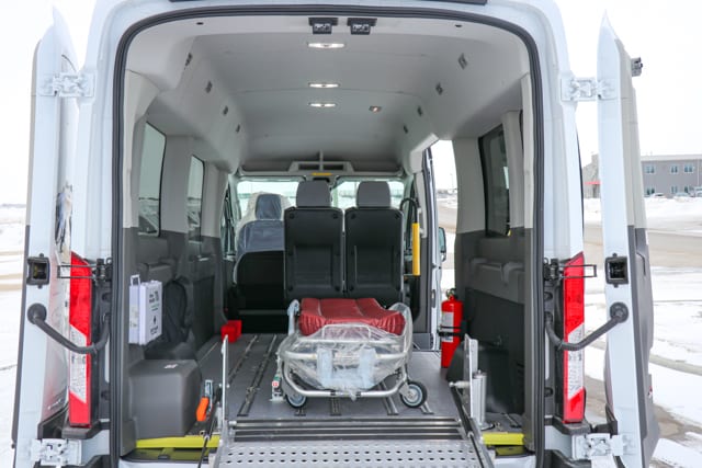 White Ford Transit van with passenger seats, floor track system and stretcher for medical transportation